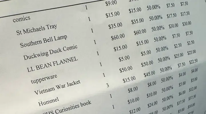 Phone photo of a printed booth sales sheet: Southern Bell Lamp $35.00, 50% off, $17.50; Duckwing Duck Comic $60.00, 50% off, $30.00; and more